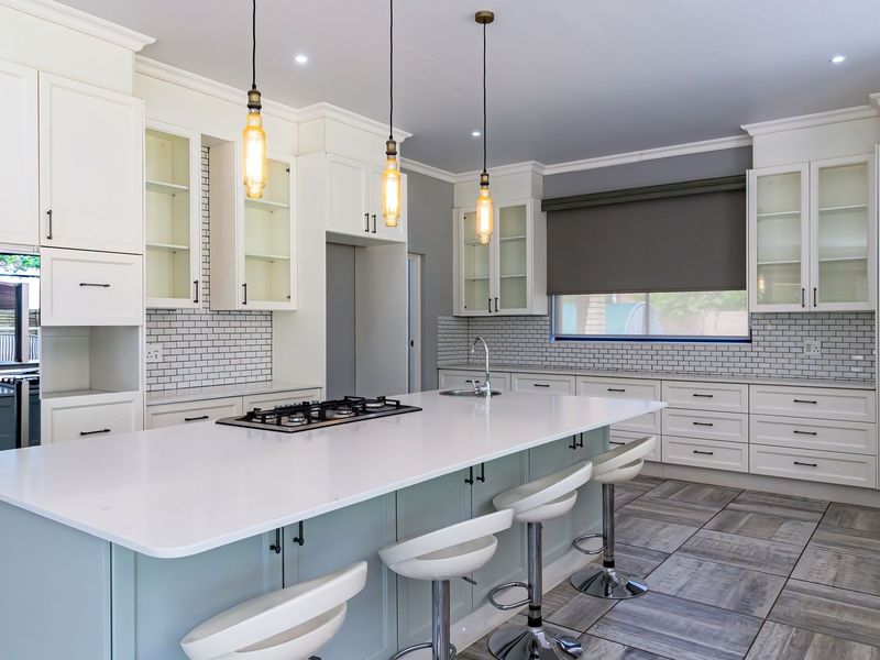 Modern kitchen featuring a large central island with quartz countertops, gas cooktop, shaker cabinetry, subway tile backsplash, and stylish pendant lighting.