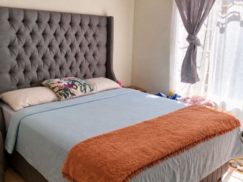 A bedroom featuring a large window with security bars and neutral wall finishes.