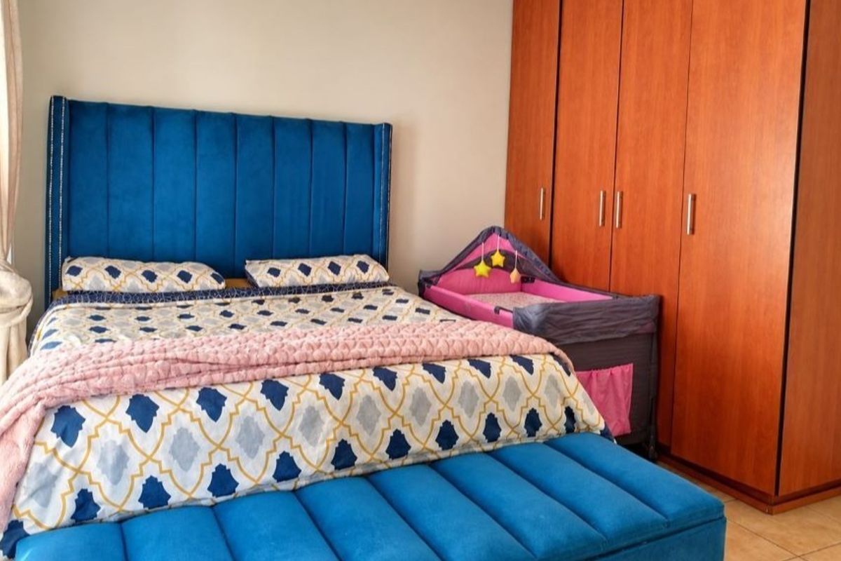 A well-maintained bedroom featuring tiled flooring and a large built-in wooden wardrobe providing ample storage space.