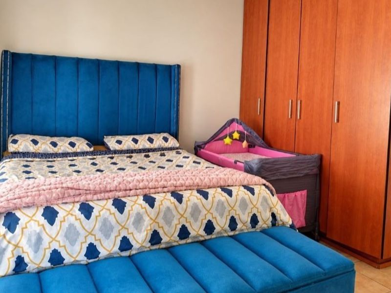 A well-maintained bedroom featuring tiled flooring and a large built-in wooden wardrobe providing ample storage space.