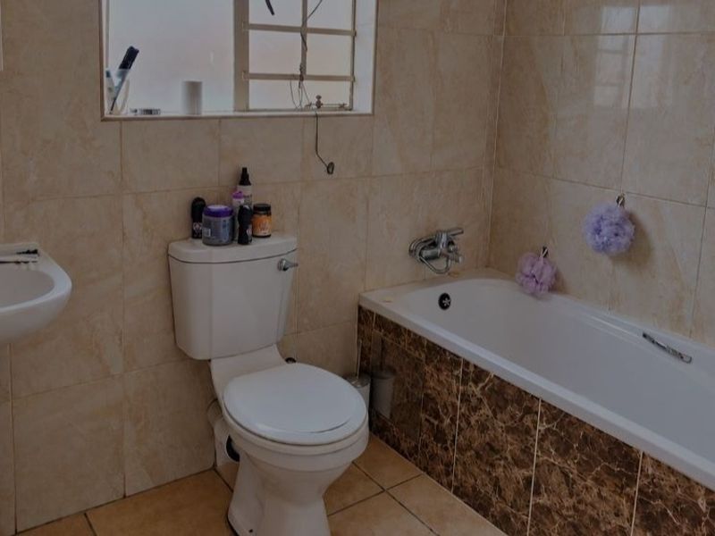 A functional bathroom featuring a pedestal basin, toilet, and bathtub with tiled walls and flooring.