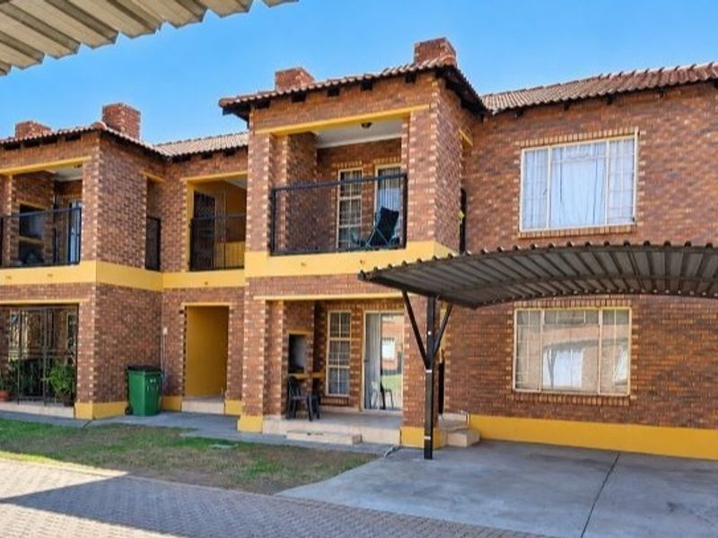A multi-story apartment complex featuring face brick construction, private balconies, and dedicated carport parking spaces.