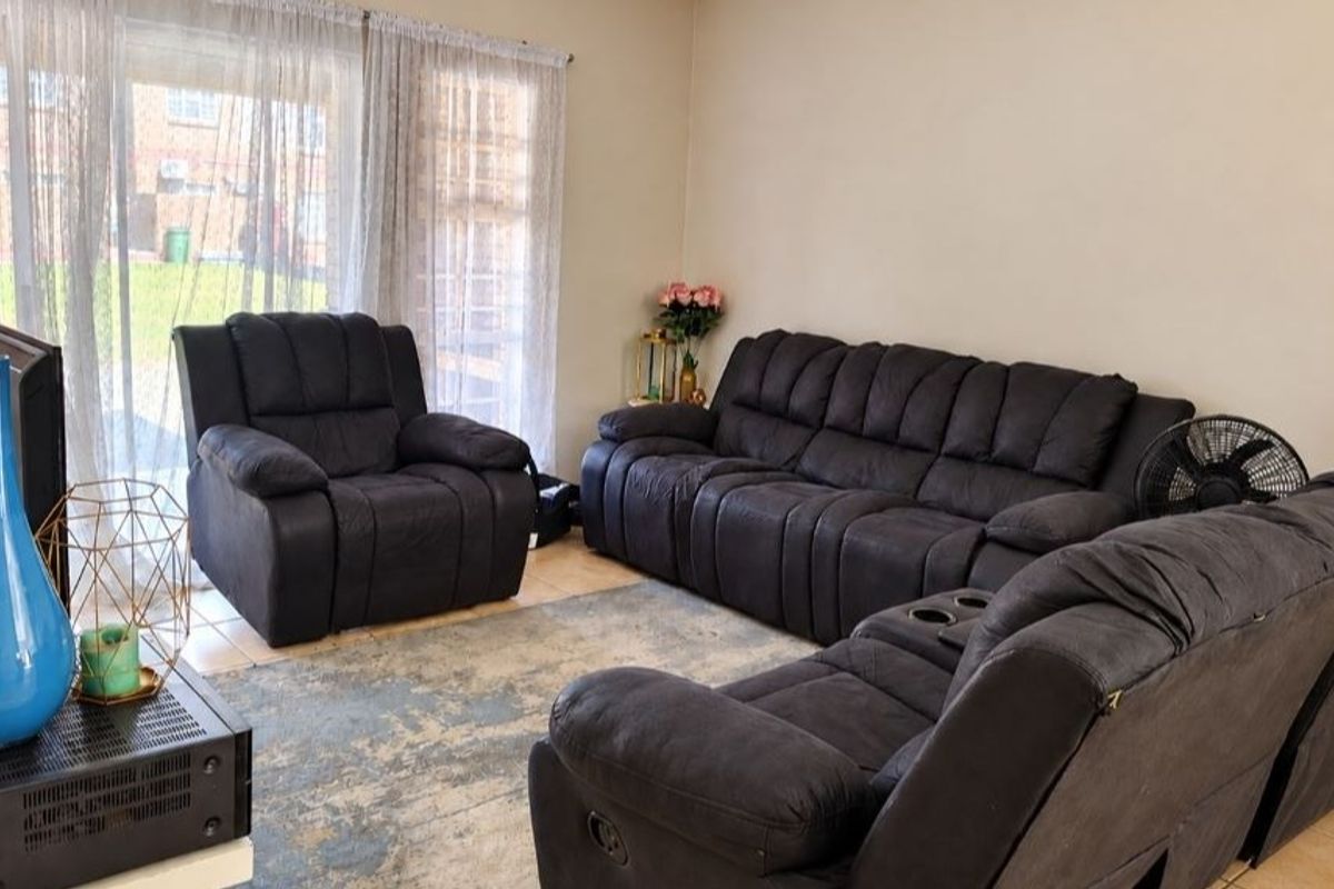 A comfortable living room featuring tiled flooring and a large sliding glass door that provides natural light and access to the exterior.