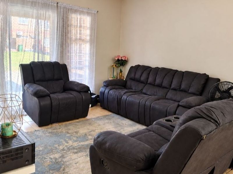 A comfortable living room featuring tiled flooring and a large sliding glass door that provides natural light and access to the exterior.