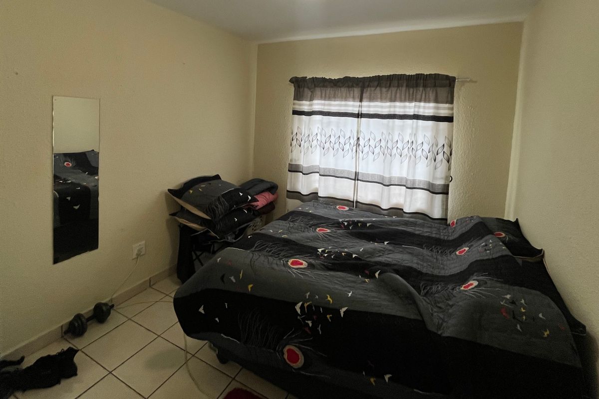 A standard bedroom featuring tiled flooring and neutral wall finishes, providing a functional space for rest.