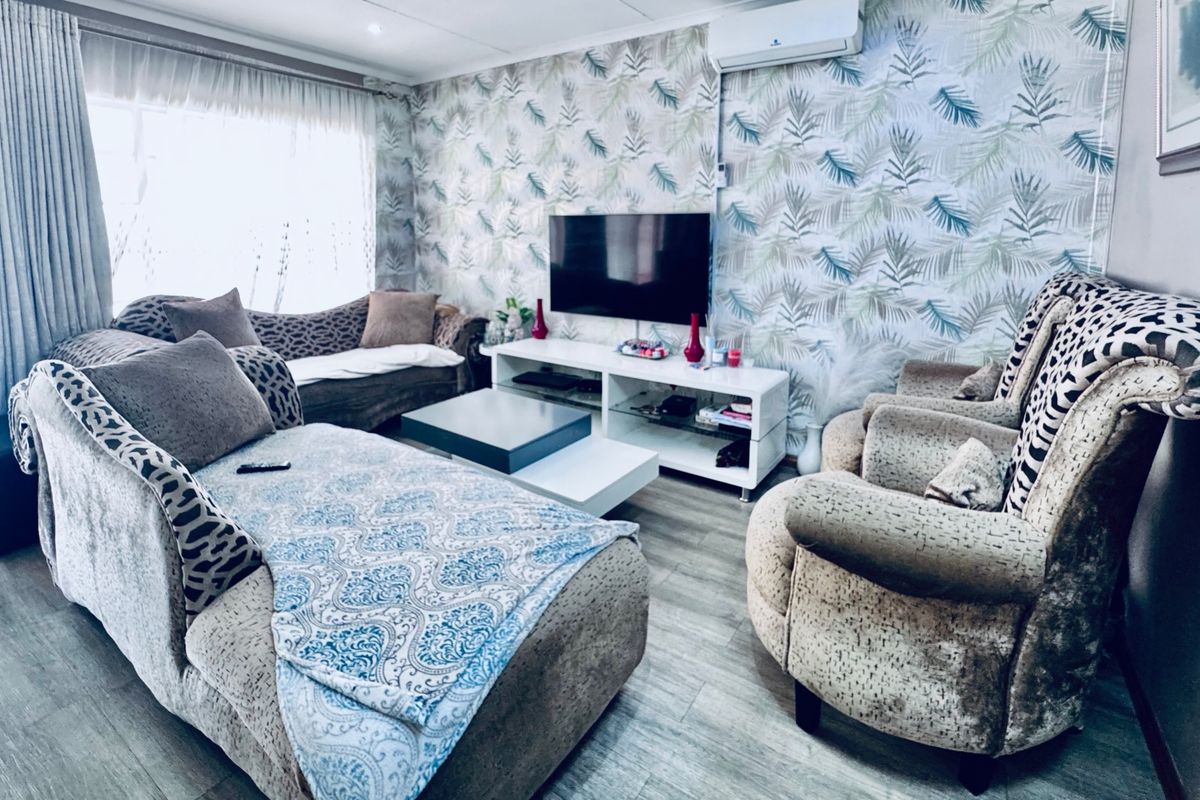 A living room featuring laminate flooring, patterned wallpaper, and a wall-mounted split-system air conditioner.