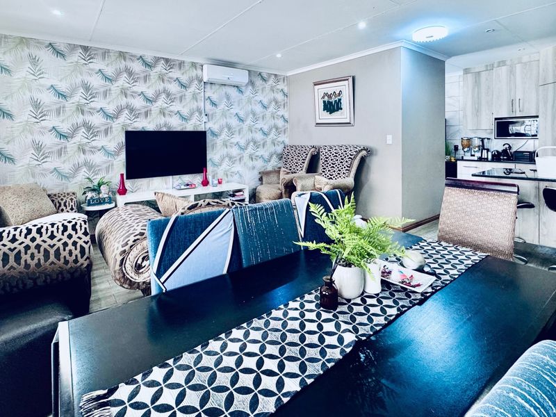 An open-plan living and dining area featuring tiled floors, recessed lighting, a split-system air conditioner, and a modern kitchen with built-in cabinetry.