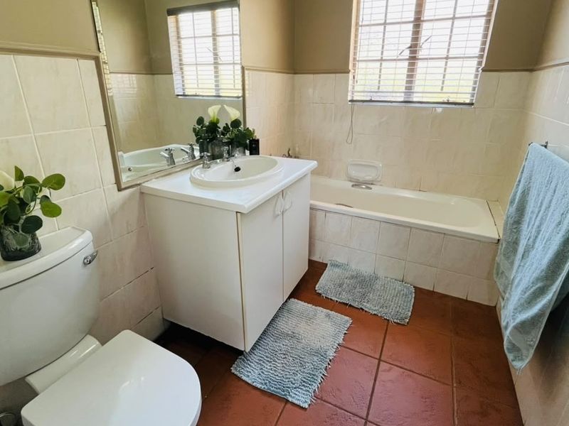 A functional bathroom featuring a built-in vanity with a ceramic basin, a standard bathtub, and tiled finishes throughout.