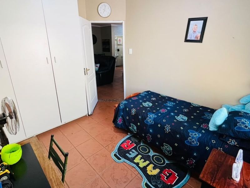 A functional bedroom featuring built-in cupboards and tiled flooring, providing a practical space with direct access to the hallway.