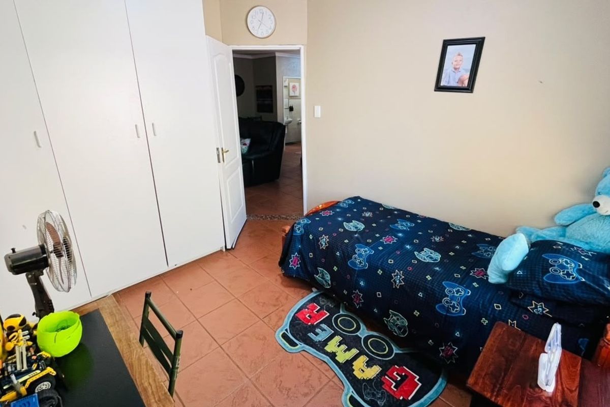 A functional bedroom featuring built-in cupboards and tiled flooring, providing a practical space with direct access to the hallway.