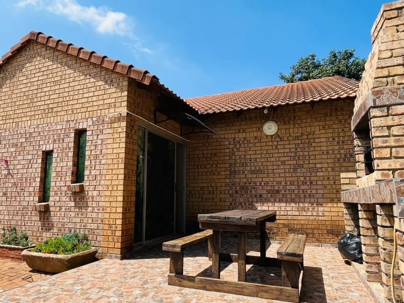 Outdoor patio area featuring a built-in brick braai, tiled flooring, and direct access to the home through a sliding glass door.