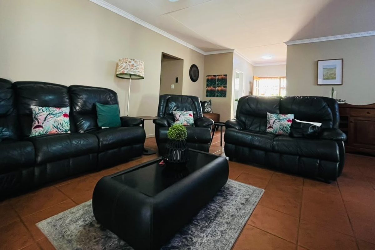 A spacious living room featuring terracotta-style tiled flooring and decorative crown molding, offering a comfortable and functional layout for relaxation.