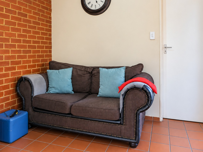 A living area featuring a distinctive exposed brick feature wall and terracotta-style tiled flooring, providing a rustic foundation for the space.