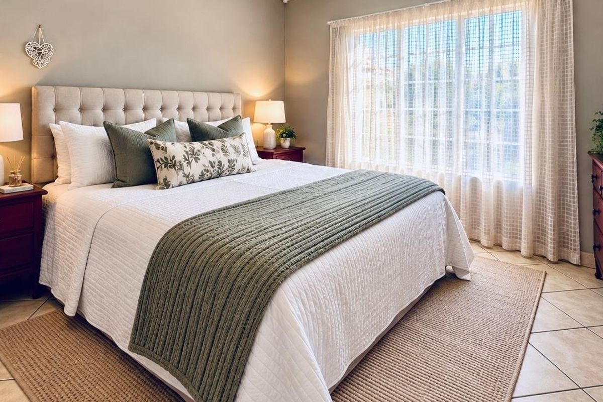 A well-maintained bedroom featuring neutral wall tones, tiled flooring, and a large window that allows for ample natural light.