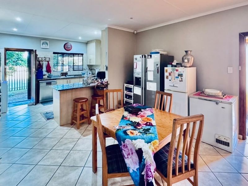 Spacious open-plan kitchen and dining area featuring tiled flooring, granite countertops, and direct access to the exterior through multiple entry points.