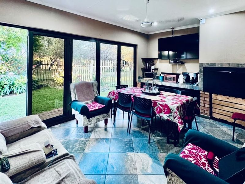 Spacious open-plan living and dining area featuring tiled floors, a built-in fireplace, and large sliding glass doors providing direct access to the garden.