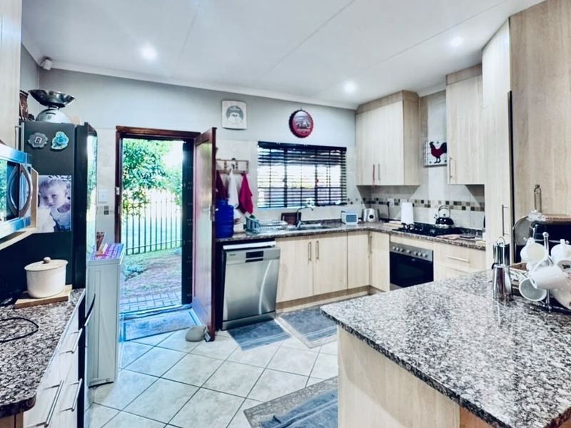 A functional kitchen featuring light wood cabinetry, granite countertops, built-in oven and hob, and direct access to the exterior.