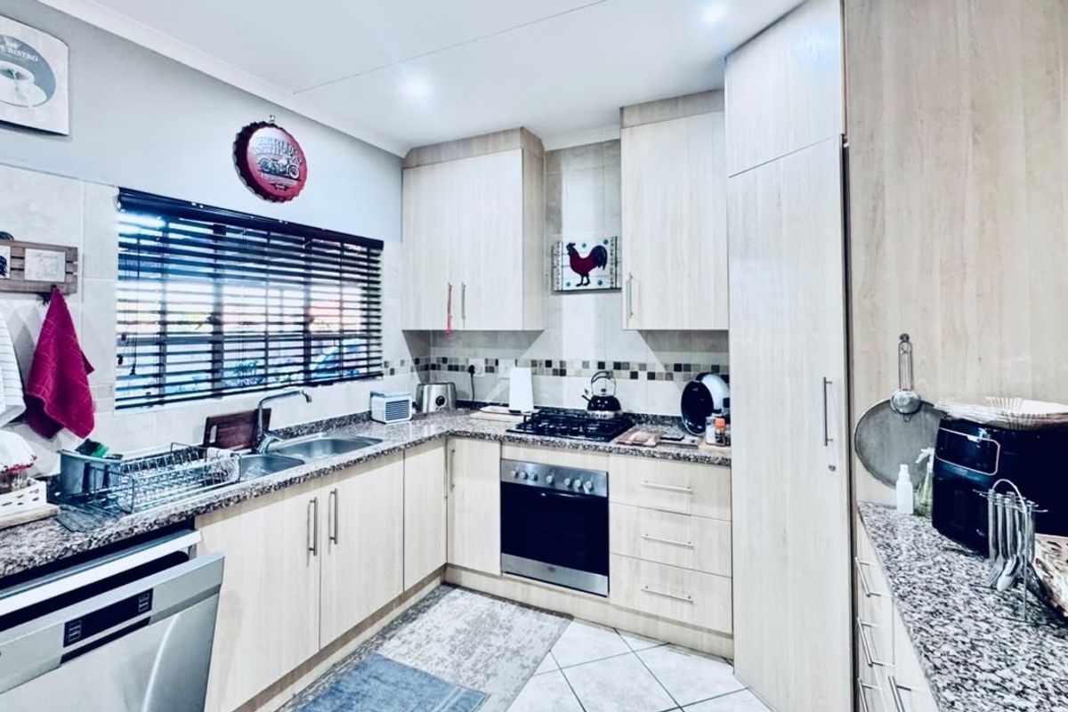 A functional kitchen featuring light wood-finish cabinetry, granite countertops, a built-in oven with gas hob, and tiled flooring.