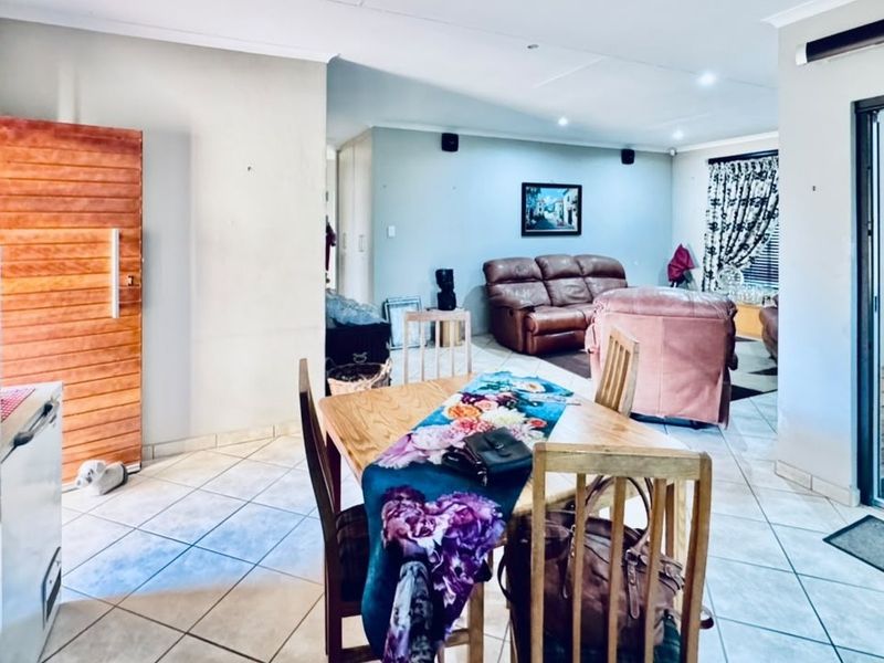 An open-plan living and dining area featuring tiled flooring, recessed lighting, and a sliding glass door providing access to the exterior.