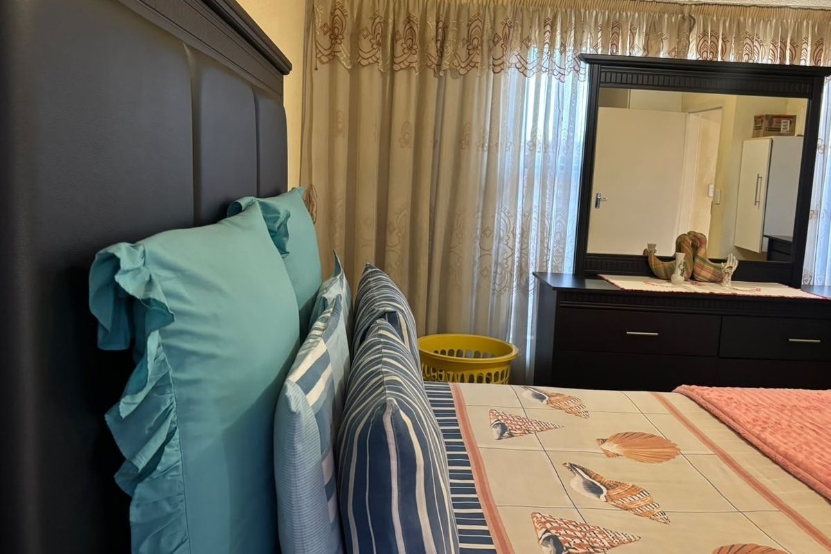 A bedroom featuring a window with installed curtain rails, providing natural light and a functional layout for a sleeping space.