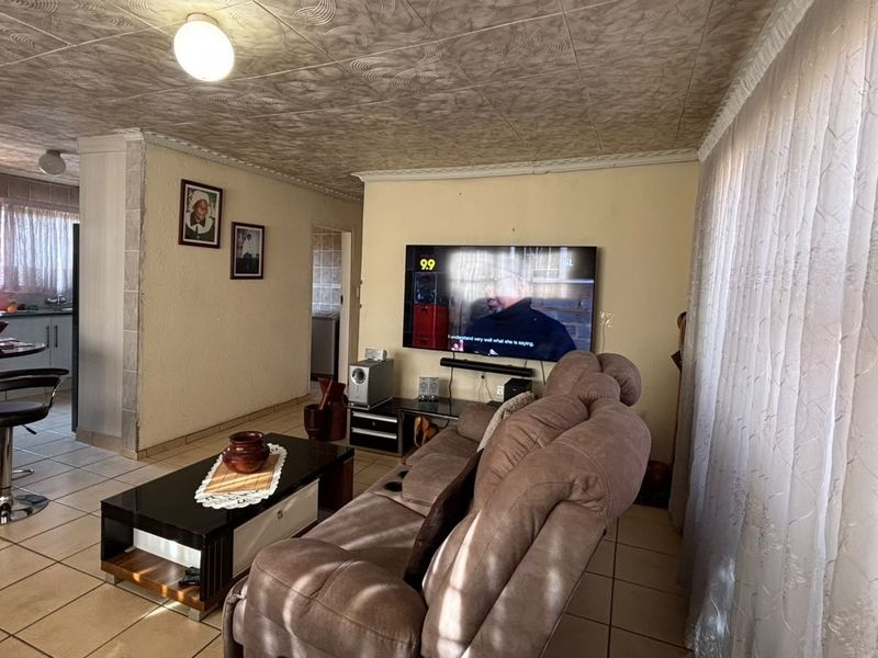 Open plan living and kitchen area featuring tiled flooring and a breakfast bar, offering a functional layout with potential for modern updates.