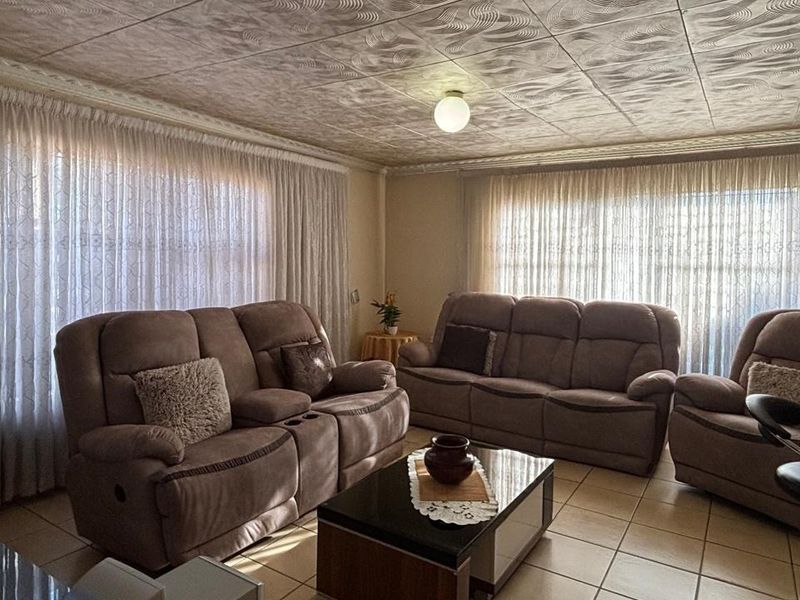 A living room featuring textured ceiling tiles and ceramic floor tiling, offering a dated but functional space ready for modernization.