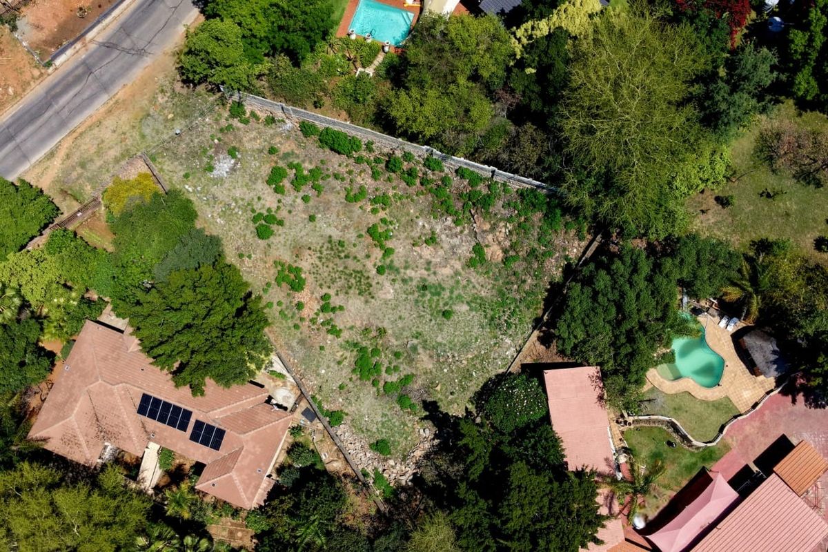 Aerial view of a vacant residential plot surrounded by established trees and neighbouring properties.