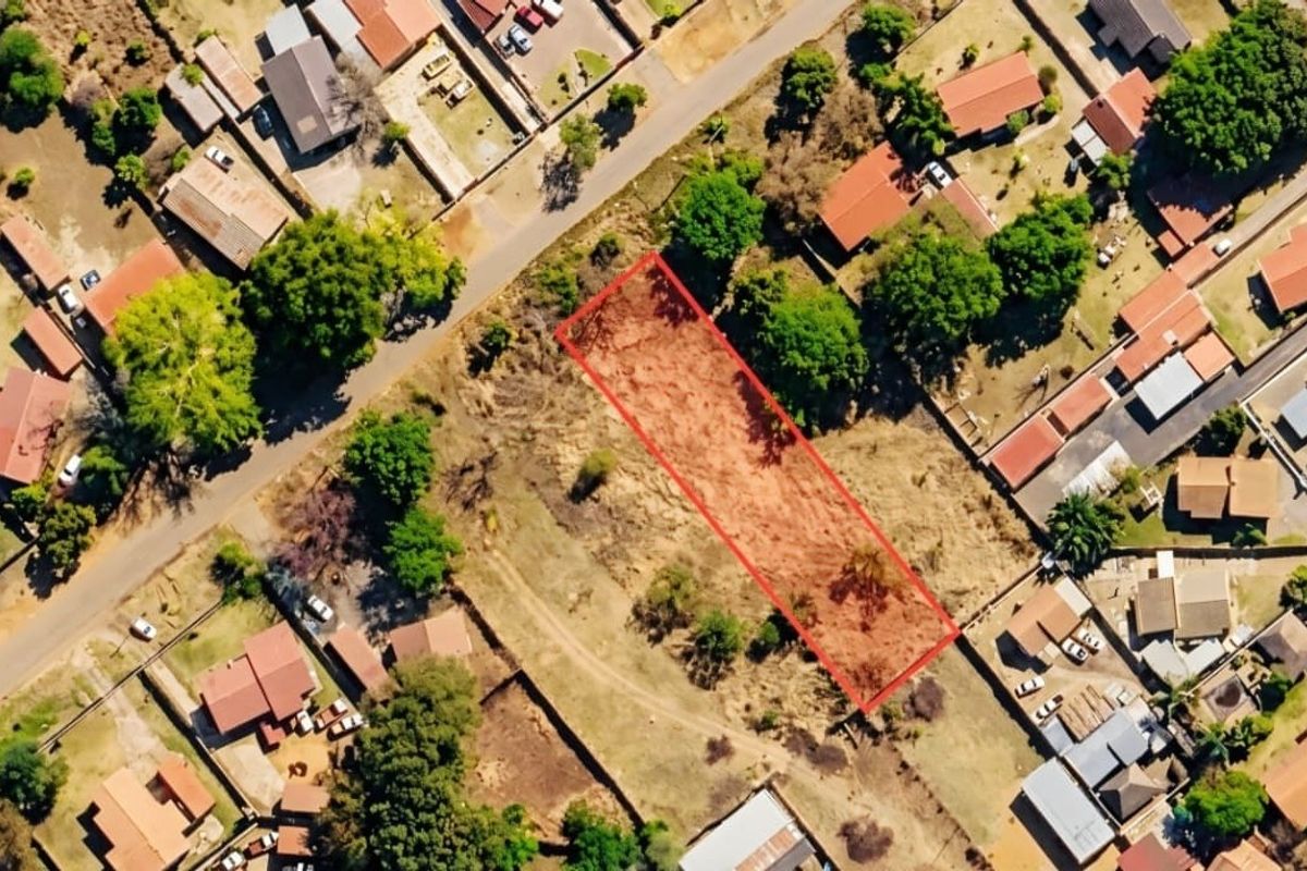 An aerial view of a vacant residential plot highlighted in red, situated within an established suburban neighborhood.