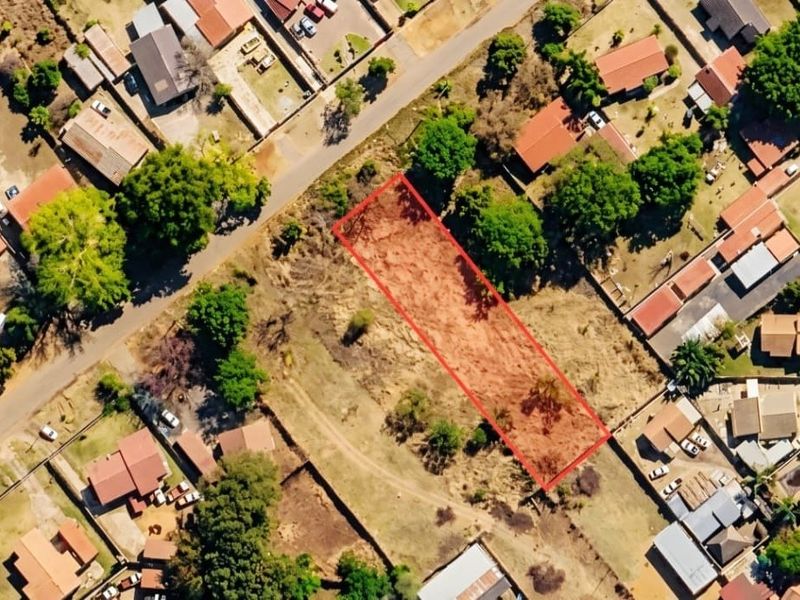 An aerial view of a vacant residential plot highlighted in red, situated within an established suburban neighborhood.