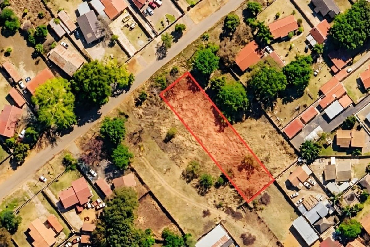 Aerial view of a vacant residential land plot highlighted in red, situated within an established suburban neighborhood.