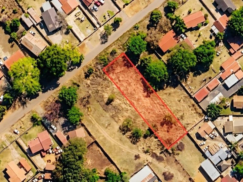 Aerial view of a vacant residential land plot highlighted in red, situated within an established suburban neighborhood.