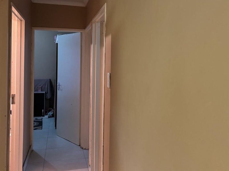 A functional hallway featuring tiled flooring and multiple doorways leading to adjacent rooms, requiring minor cosmetic updates to the wall finishes.
