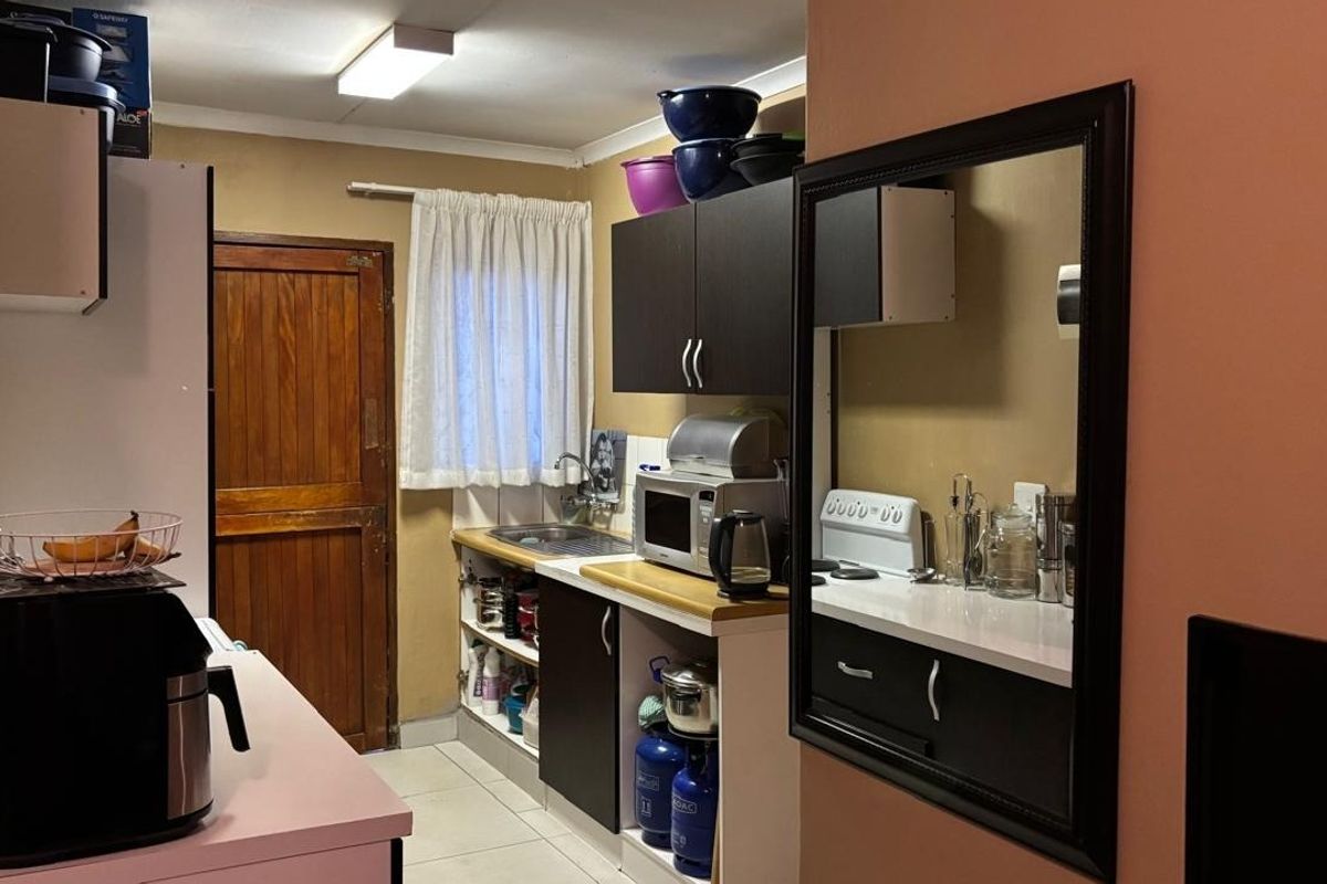A functional kitchen featuring dark cabinetry, laminate countertops, a stainless steel sink, and tiled flooring, providing a practical workspace.