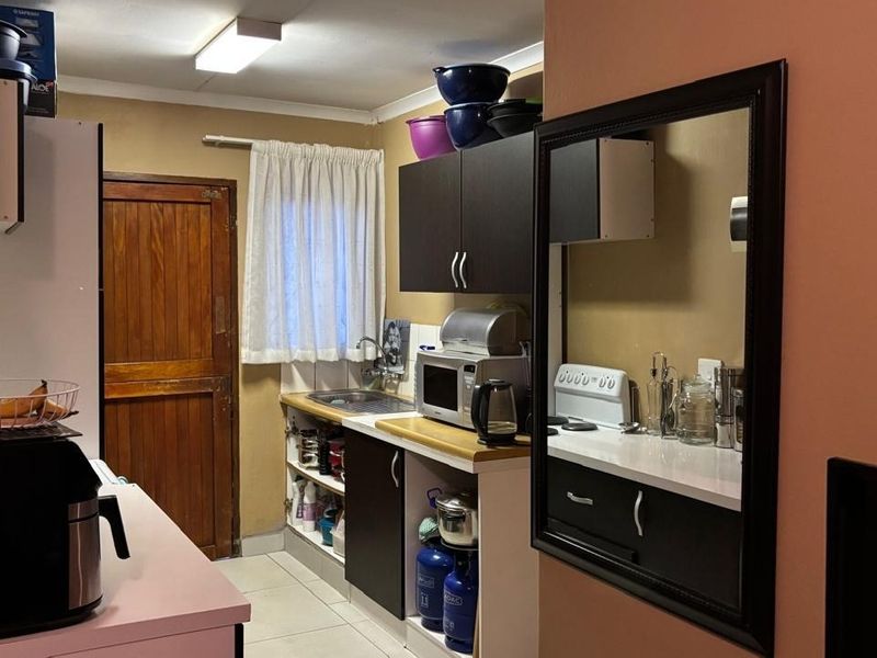 A functional kitchen featuring dark cabinetry, laminate countertops, a stainless steel sink, and tiled flooring, providing a practical workspace.