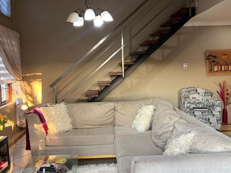 A comfortable living room featuring a modern staircase with a stainless steel balustrade and tiled flooring.