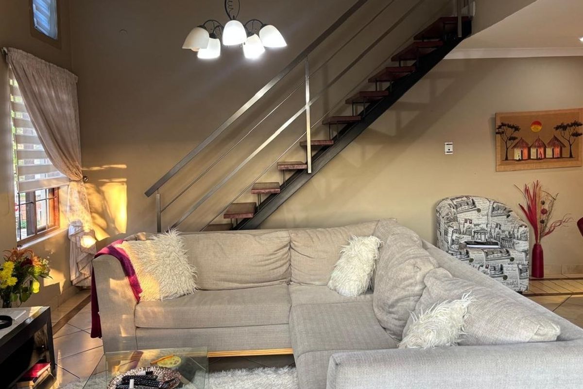 A comfortable living room featuring a modern staircase with a stainless steel balustrade and tiled flooring.