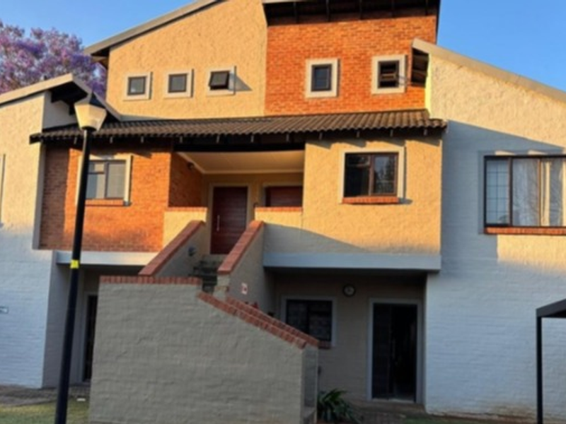Front elevation of a multi-story residential building featuring a combination of brick and stucco finishes, an external staircase, and an integrated carport.