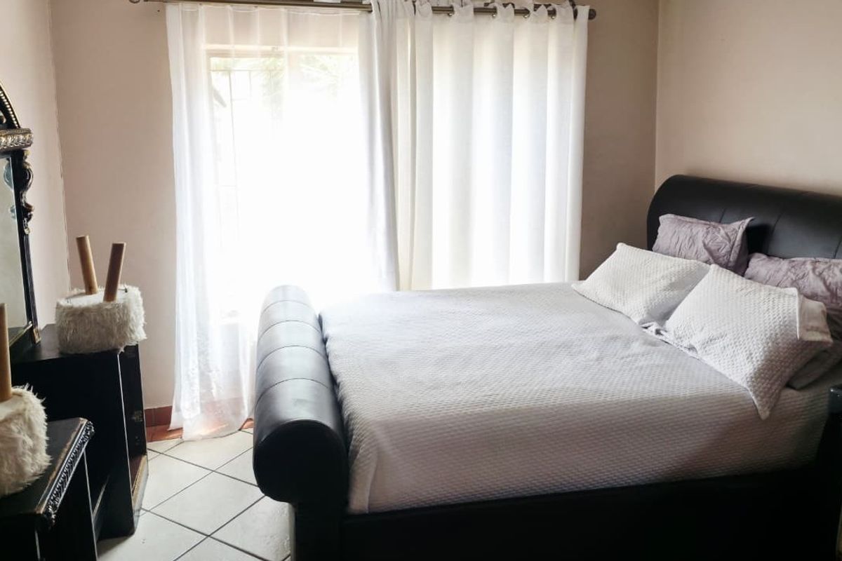 A bedroom featuring tiled flooring and natural light through a window with installed curtain rods.