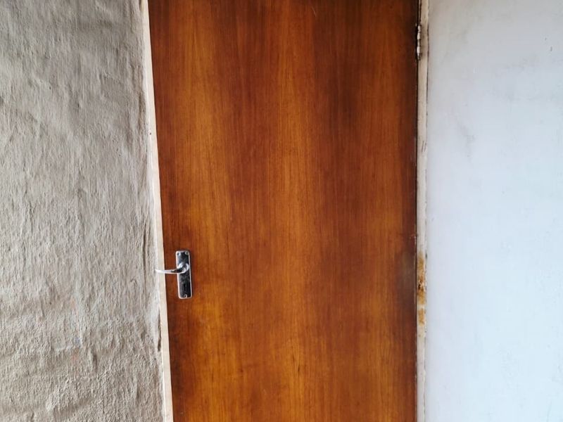 A close-up view of a wooden interior door set between two walls with varying textures and finishes.