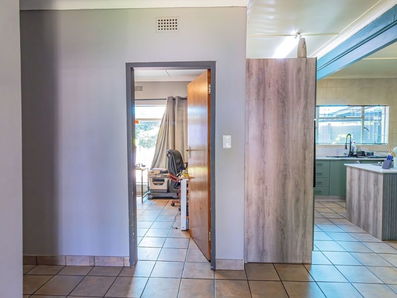 Open plan living area featuring tiled flooring and a kitchen with island cabinetry, providing a functional layout with access to an adjoining room.