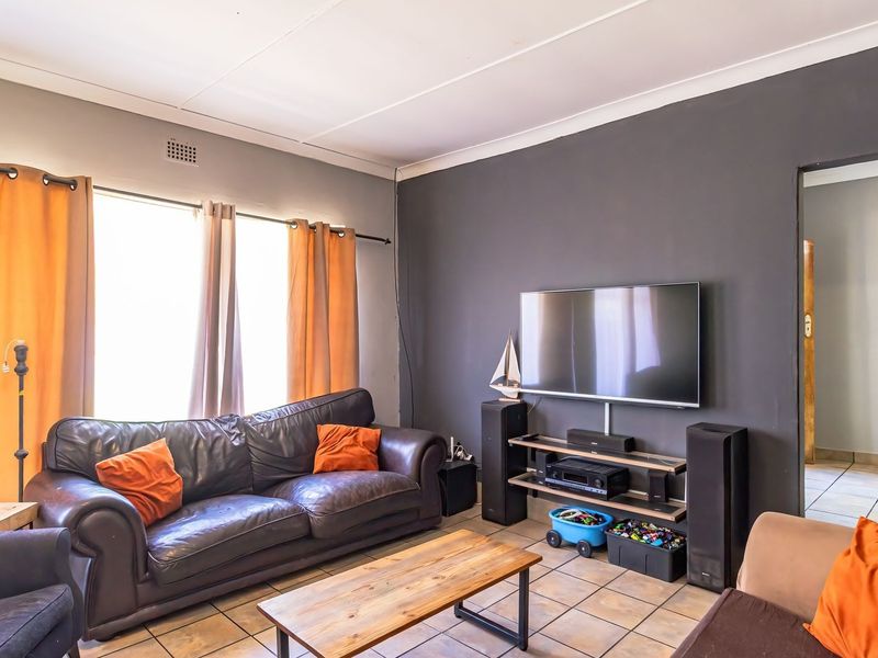 A comfortable living room featuring tiled flooring, coved ceilings, and a neutral color palette, providing a functional space for relaxation.