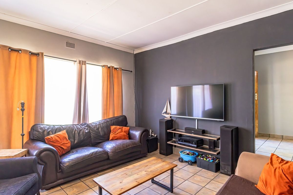 A comfortable living room featuring tiled flooring, coved ceilings, and a neutral color palette, providing a functional space for relaxation.