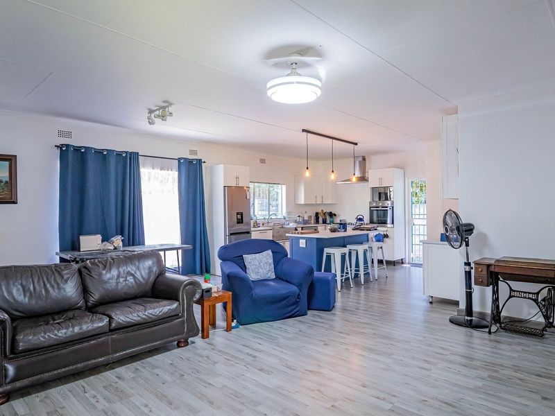 Spacious open-plan living area featuring a modern kitchen with a central island, built-in appliances, and light-toned laminate flooring throughout.