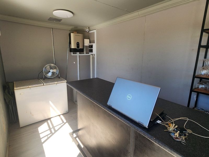 A functional bar area featuring a built-in counter, fixed shelving, and wall-mounted utility services, suitable for entertainment or hospitality use.