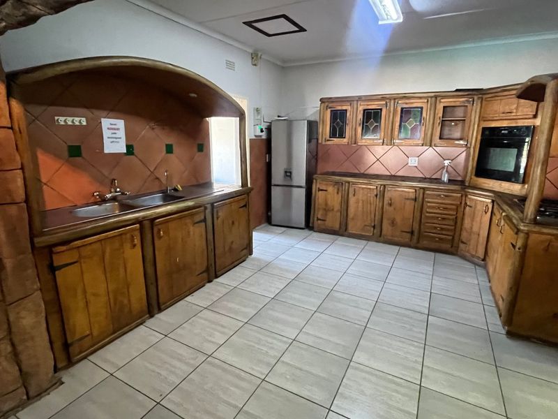 A spacious kitchen featuring extensive wooden cabinetry, tiled backsplash, and built-in cooking appliances, offering a traditional aesthetic with potential for modern updates.