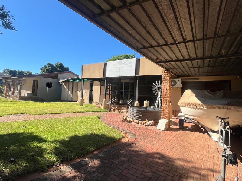 Front exterior view of the property featuring a paved driveway, covered carport, and landscaped lawn area.