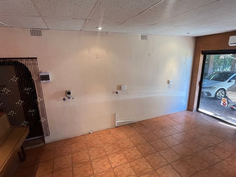 An empty utility or laundry space featuring tiled flooring, wall-mounted air conditioning, and existing plumbing connections for appliances.
