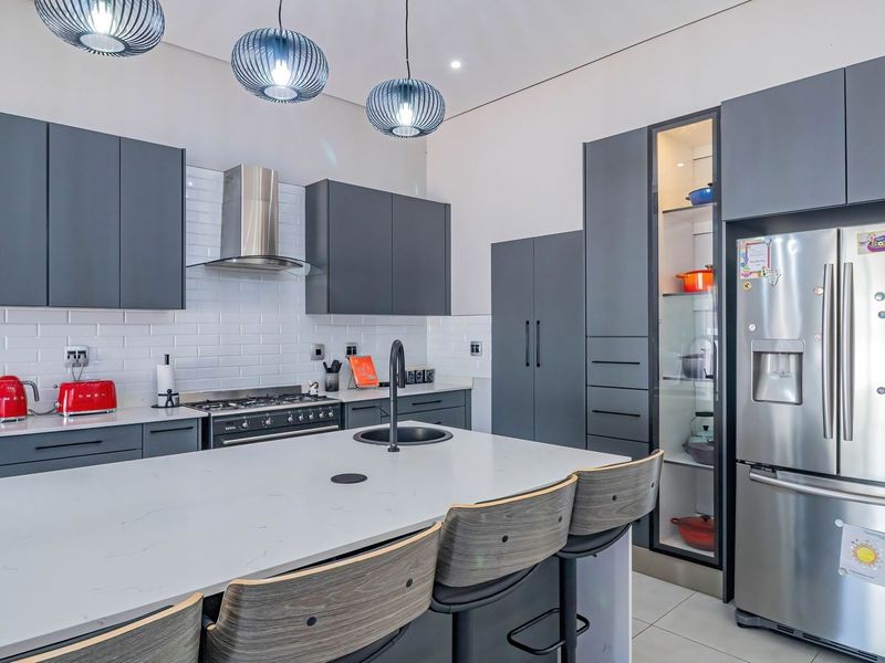 Modern kitchen featuring dark grey cabinetry, a central island with quartz countertops, subway tile backsplash, and high-end stainless steel appliances.