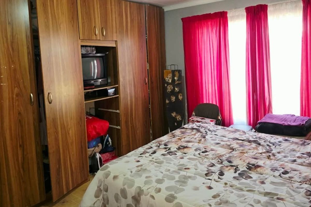 A bedroom featuring extensive floor-to-ceiling built-in wooden cupboards providing ample storage space.