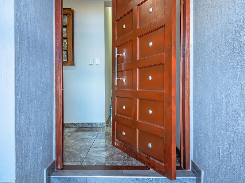A bright entrance area featuring a solid wood panel door and tiled flooring, leading into the interior of the home.